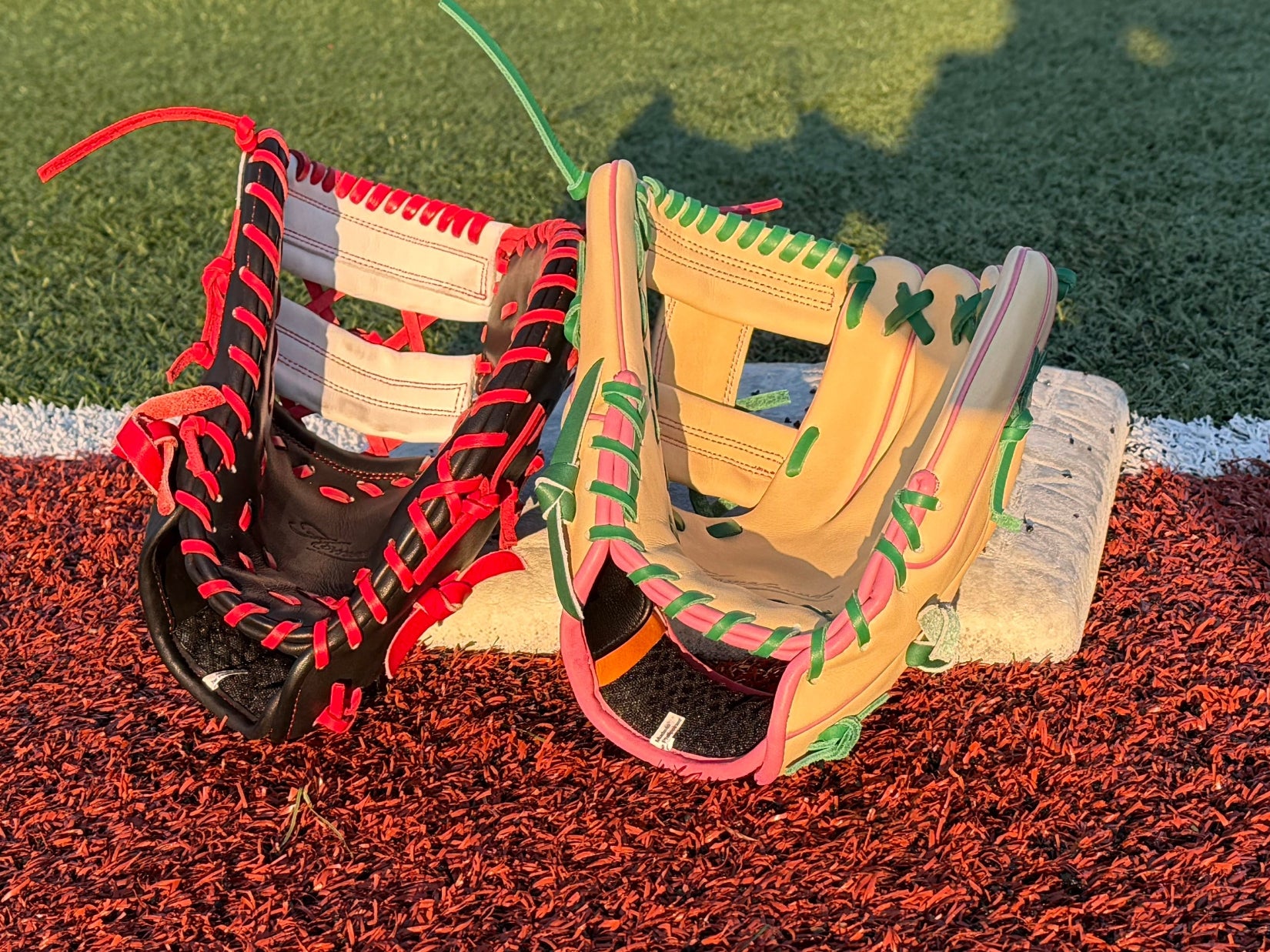 Two baseball gloves propped up against first base. 